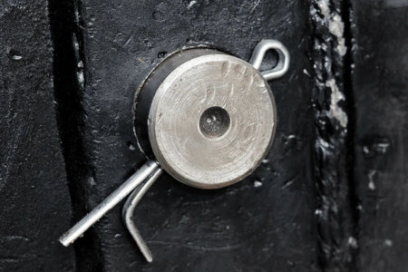 Close-up of a metal rod with cotter  pin mechanism on a dark surface