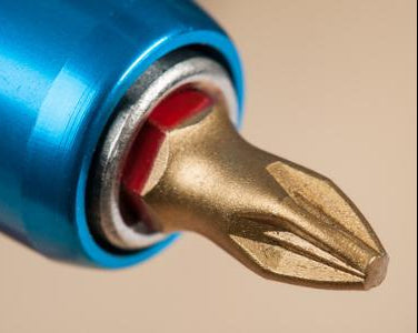 Close-up of a drill bit with a blue handle on a beige background