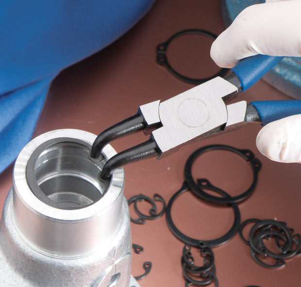 Close-up of a metal fitting with pliers and gaskets on a brown surface