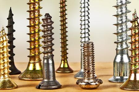 Collection of various screws on a wooden surface with a neutral background